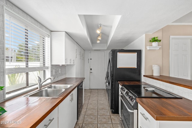 kitchen with black dishwasher, decorative backsplash, stainless steel range with electric stovetop, sink, and white cabinetry