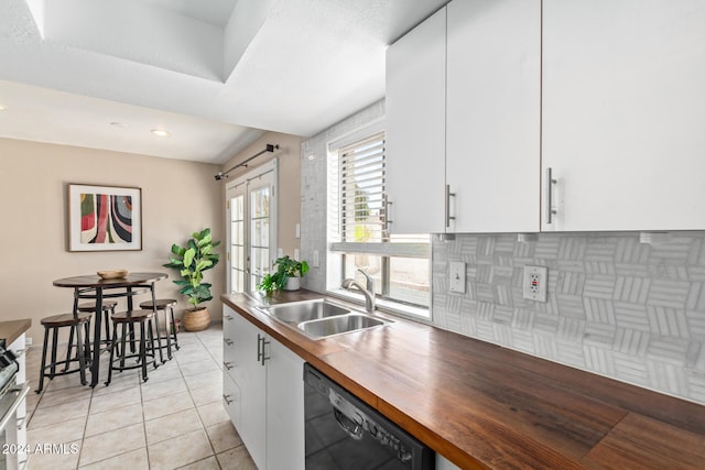 kitchen with tasteful backsplash, light tile patterned floors, sink, white cabinets, and dishwasher