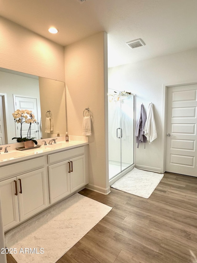 bathroom with hardwood / wood-style flooring, vanity, and an enclosed shower