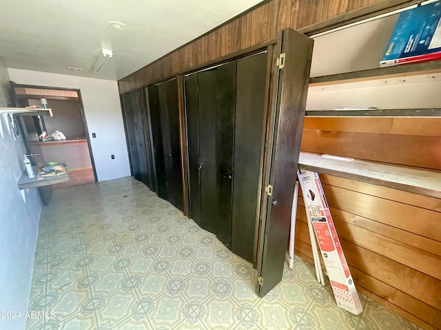 interior space with light tile flooring and wood walls