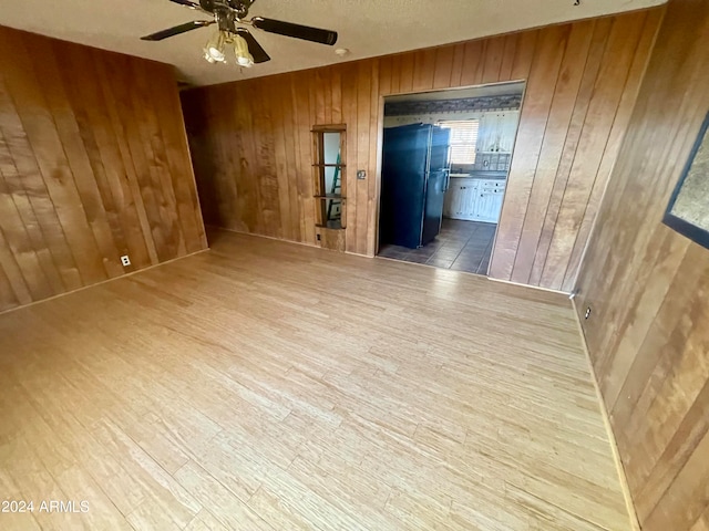 spare room featuring ceiling fan, wood walls, and dark wood-type flooring