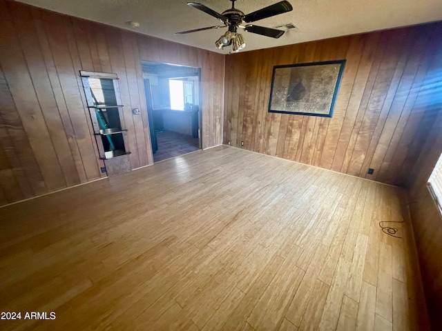 unfurnished room featuring wood walls, ceiling fan, and dark hardwood / wood-style flooring