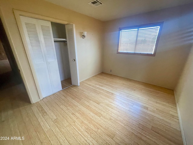 unfurnished bedroom with light hardwood / wood-style floors and a closet