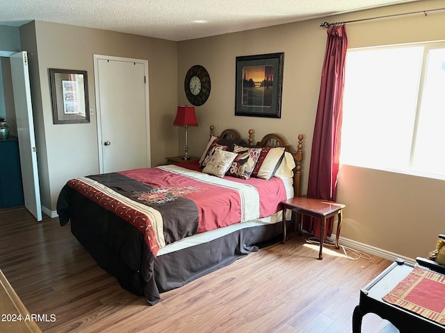 bedroom featuring a textured ceiling and light hardwood / wood-style flooring