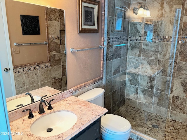 bathroom with tiled shower, vanity, and toilet