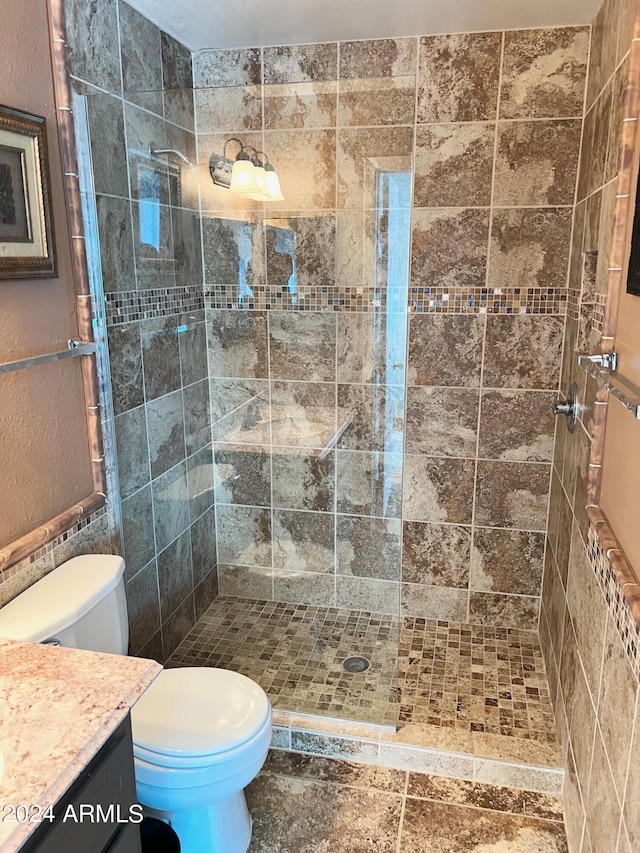 bathroom featuring a tile shower, vanity, and toilet