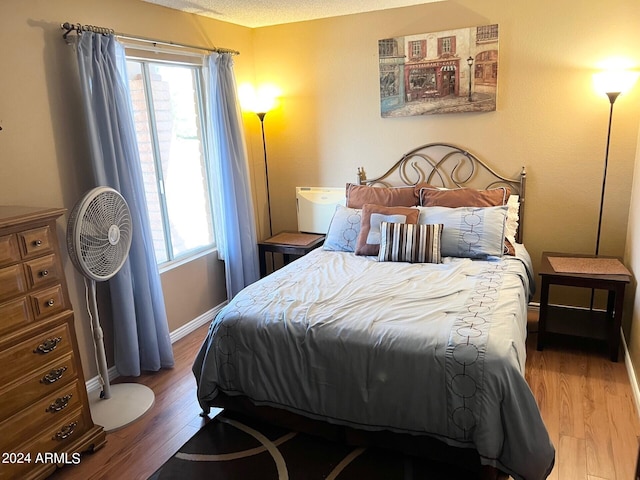 bedroom with a textured ceiling and wood-type flooring