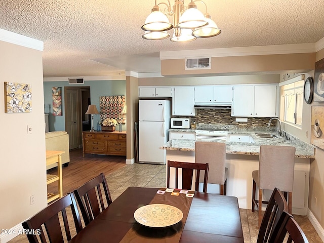 dining space featuring a textured ceiling, light hardwood / wood-style flooring, and ornamental molding