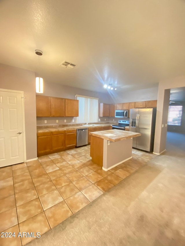 kitchen featuring decorative light fixtures, a center island, light tile patterned flooring, and stainless steel appliances