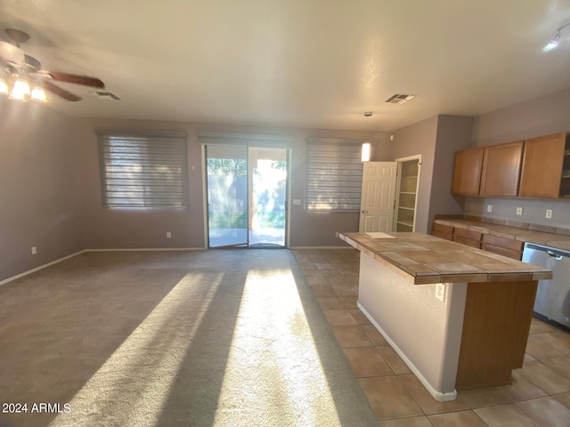 kitchen with tile countertops, dishwasher, pendant lighting, carpet flooring, and ceiling fan