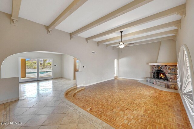 10239 N 125th St, Scottsdale, AZ 85259 - unfurnished living room with arched walkways, a ceiling fan, beamed ceiling, a stone fireplace, and baseboards