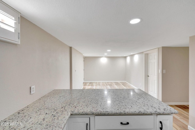 10239 N 125th St, Scottsdale, AZ 85259 - kitchen with light wood-type flooring, a peninsula, white cabinets, light stone countertops, and baseboards