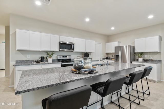 kitchen featuring stainless steel appliances, an island with sink, and white cabinets