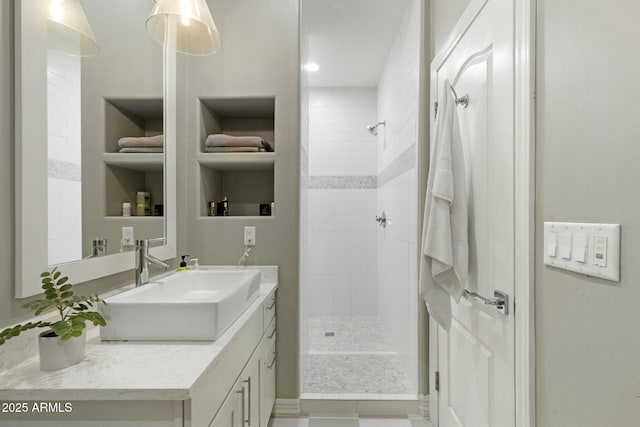 full bathroom featuring tiled shower and vanity