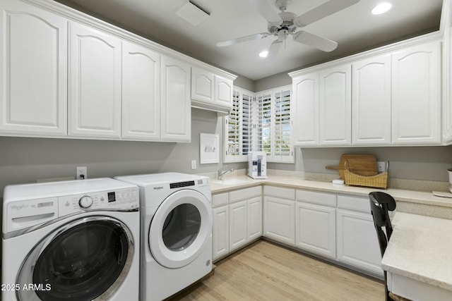 clothes washing area with washing machine and dryer, a sink, a ceiling fan, cabinet space, and light wood finished floors