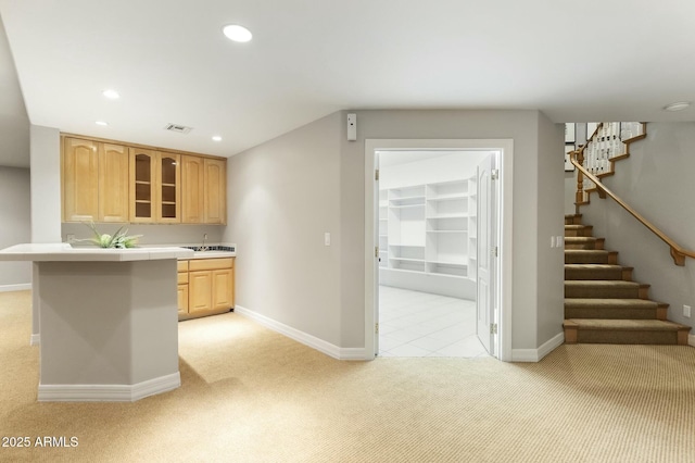 kitchen featuring visible vents, light colored carpet, glass insert cabinets, light brown cabinetry, and recessed lighting