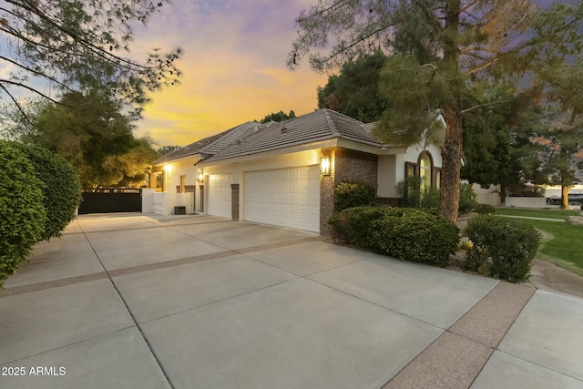 view of front facade with a garage, brick siding, fence, driveway, and stucco siding