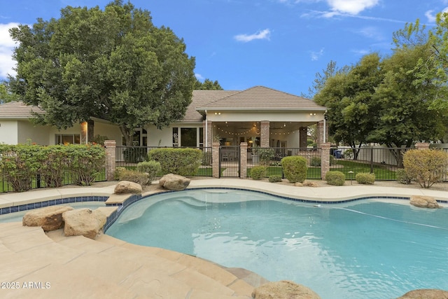 view of swimming pool featuring a pool with connected hot tub, fence, and a patio