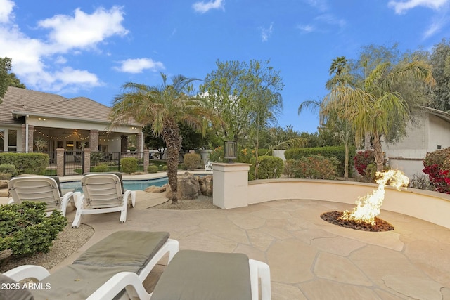 view of patio / terrace featuring an outdoor fire pit, fence, and an outdoor pool