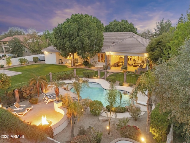 pool at dusk with a fenced in pool, a lawn, a fenced backyard, a patio area, and an outdoor living space