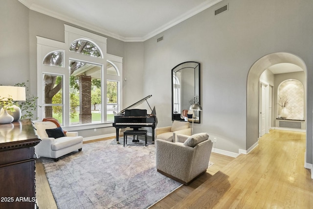 interior space featuring arched walkways, ornamental molding, wood finished floors, and baseboards