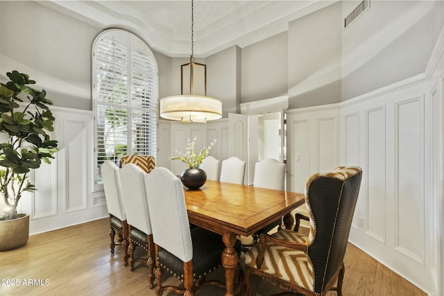 dining room with wainscoting, visible vents, a decorative wall, and light wood finished floors