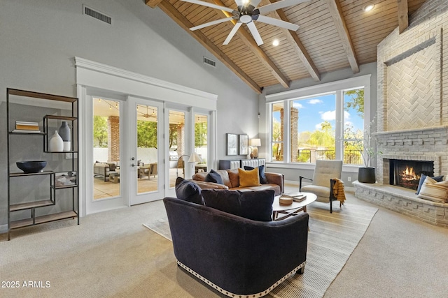 living area with a brick fireplace, visible vents, and beam ceiling