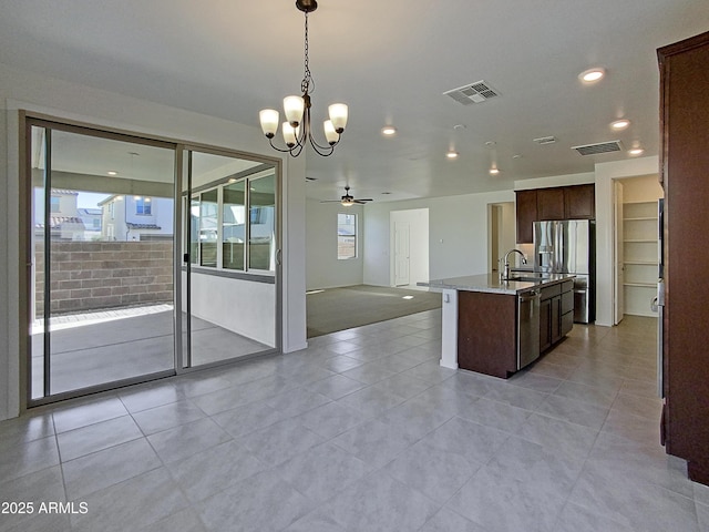 kitchen with ceiling fan, hanging light fixtures, light tile patterned flooring, an island with sink, and stainless steel appliances