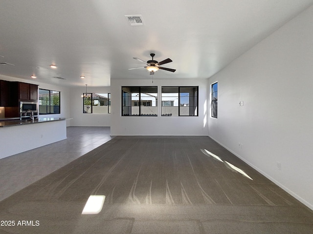 unfurnished living room featuring sink, ceiling fan, and dark carpet