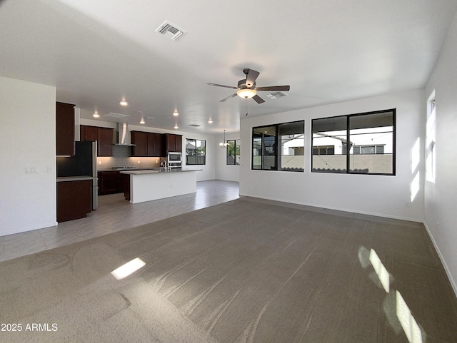 unfurnished living room featuring sink, ceiling fan, and carpet flooring