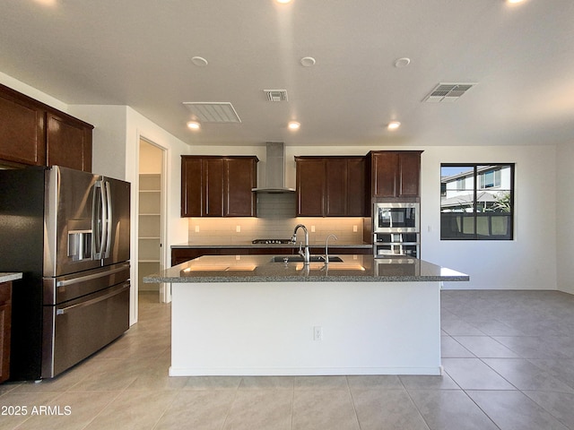 kitchen featuring sink, a center island with sink, wall chimney range hood, and stainless steel appliances