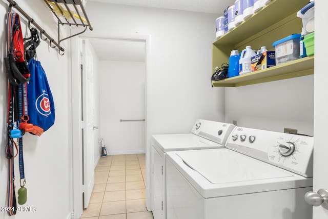 washroom with washer and dryer, light tile patterned floors, and a textured ceiling