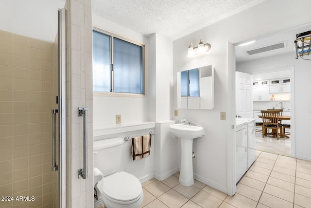 bathroom with tile patterned floors, separate washer and dryer, a shower with shower door, and a textured ceiling