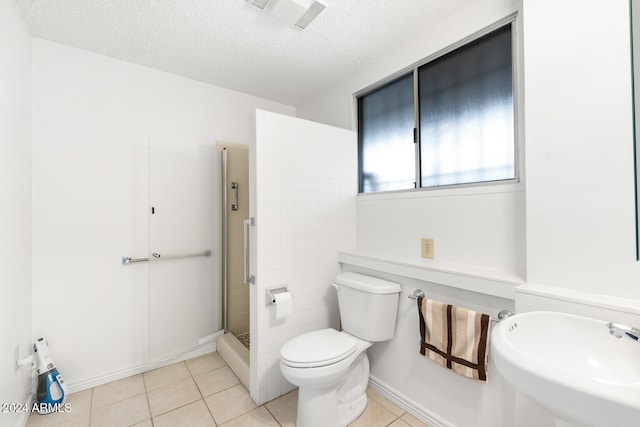 bathroom with toilet, a tile shower, a textured ceiling, and tile patterned floors