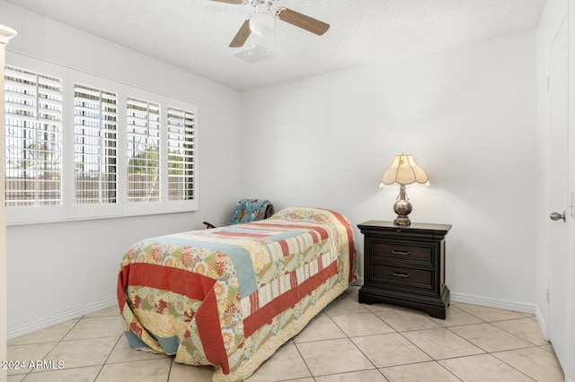 bedroom featuring ceiling fan, light tile patterned flooring, and a textured ceiling