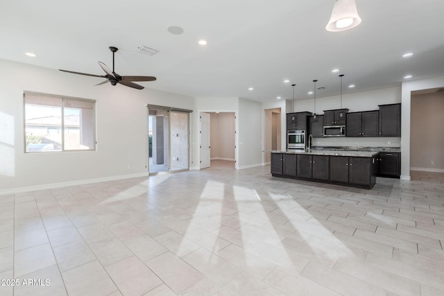 kitchen with ceiling fan, sink, hanging light fixtures, a kitchen island with sink, and appliances with stainless steel finishes