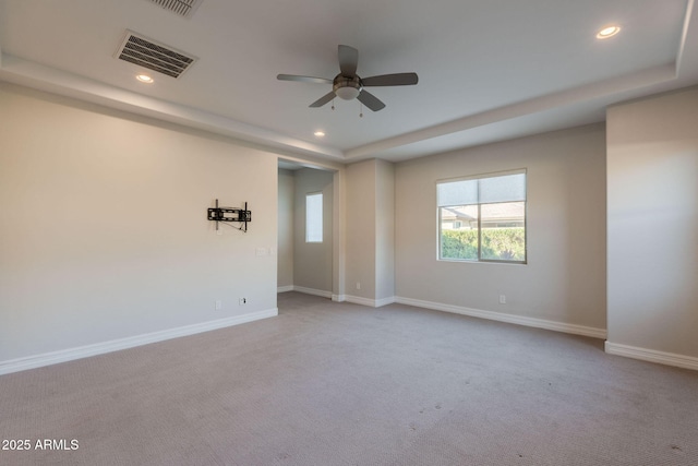 carpeted empty room with ceiling fan and a raised ceiling