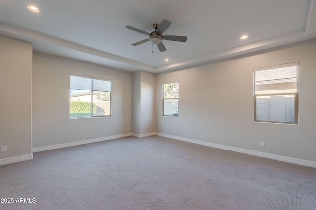 unfurnished room featuring ceiling fan, light colored carpet, and a tray ceiling