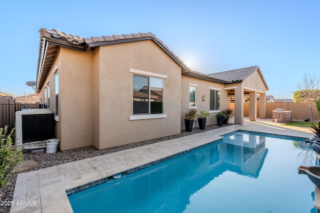 rear view of house featuring cooling unit, a patio area, and a fenced in pool