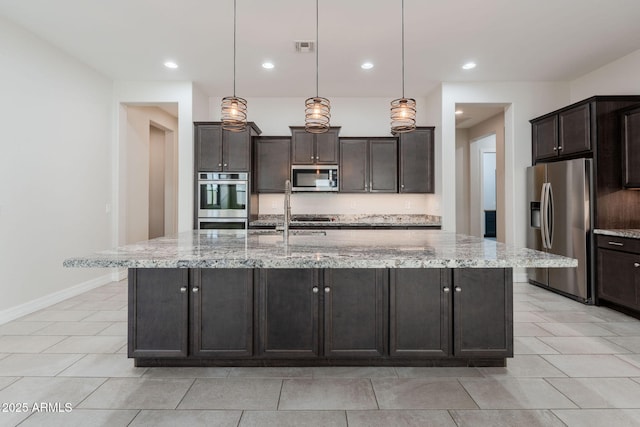 kitchen featuring decorative light fixtures, light stone countertops, stainless steel appliances, and a center island with sink