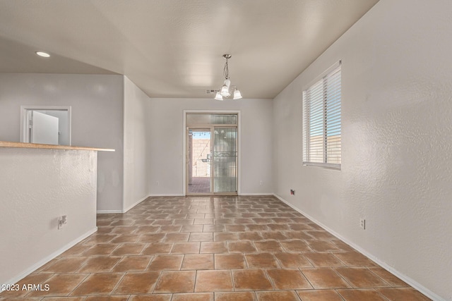 unfurnished room featuring tile patterned flooring and an inviting chandelier