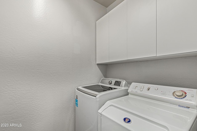 laundry room with separate washer and dryer and cabinets