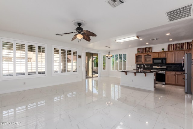 kitchen with tasteful backsplash, a breakfast bar, ceiling fan with notable chandelier, stainless steel appliances, and decorative light fixtures