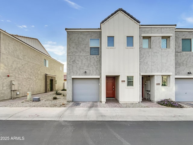 townhome / multi-family property with board and batten siding, a garage, and stucco siding