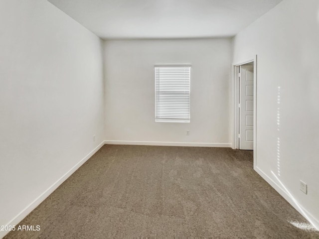 carpeted empty room featuring baseboards