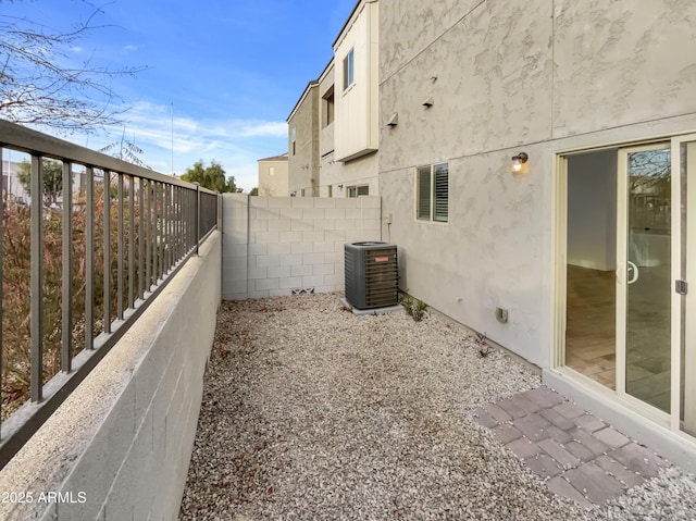 view of side of property with central air condition unit, fence, and stucco siding