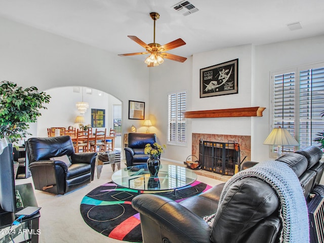 living room with ceiling fan, lofted ceiling, a tiled fireplace, and carpet