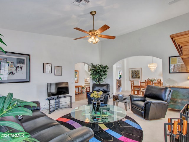 carpeted living room with ceiling fan with notable chandelier