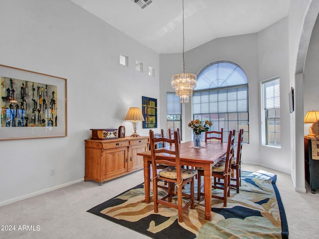 dining space with a notable chandelier, light colored carpet, and high vaulted ceiling