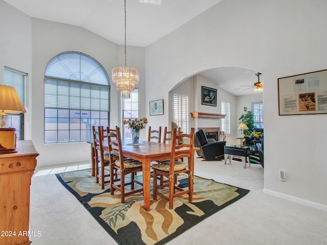 dining room featuring light colored carpet, ceiling fan with notable chandelier, and lofted ceiling